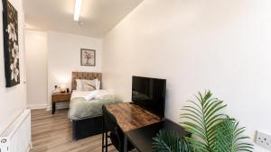 a bedroom with a bed and a desk with a television at Sangha House - Ensuite Rooms with Shared Kitchen Facilities in Leicester
