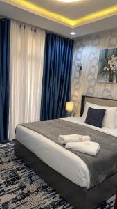 ein Schlafzimmer mit einem großen Bett und blauen Vorhängen in der Unterkunft Empire M in Kinshasa