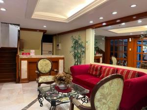 a living room with a red couch and a table at The Manor Hotel in Davao City