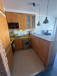 a kitchen with wooden cabinets and a washing machine at Apartamento Bamuxela in Vigo