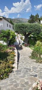 a stone walk way with a tree and flowers at Cortijo La Joya in Lanjarón