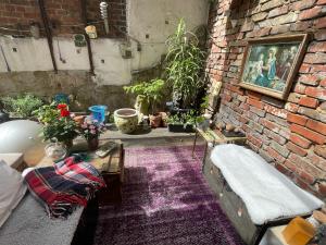 a room with a brick wall with a couch and flowers at Zimmer in Künstlerwohnung in Stuttgart