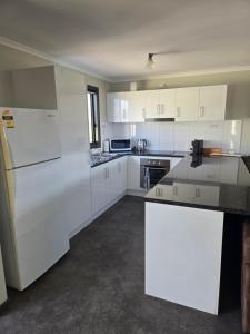 a kitchen with white cabinets and a white refrigerator at Wudinna Crow's Nest in Wudinna