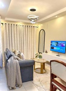 a living room with a blue couch and a tv at SerenityLoft by Gloria in Thika