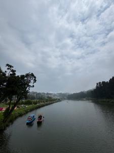 three boats in a river under a cloudy sky at The Mirik Address in Mirik