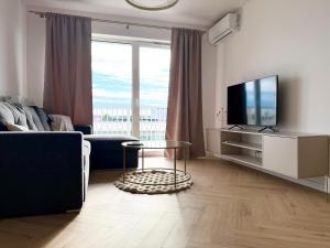 a living room with a tv and a couch and a table at Kaszmirowy Apartament in Mrągowo