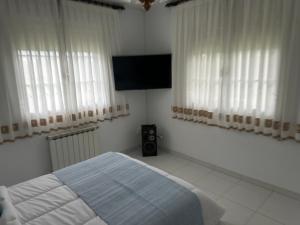 a bedroom with a bed and a flat screen tv at Refugio Rural A Revolta in Bergazo