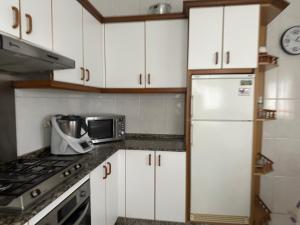 a kitchen with white cabinets and a white refrigerator at Refugio Rural A Revolta in Bergazo