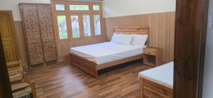 a small bedroom with a bed and two windows at Basera Lodges in Nathia Gali