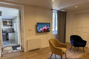 a living room with two chairs and a television on the wall at L'Annexe du Piton in Sancerre