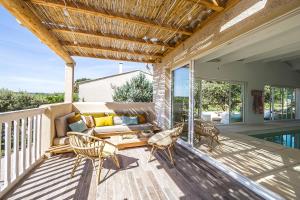 a patio with a couch and chairs on a deck at La Villa Les Petits Gardons in Castillon-du-Gard