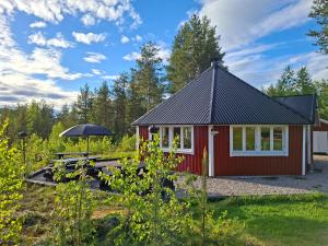 eine rote Hütte mit einem Tisch und einem Sonnenschirm in der Unterkunft Arctic Ranch in Överkalix