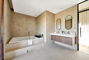 ein Badezimmer mit Badewanne, Waschbecken und Spiegel in der Unterkunft Hôtel Éole Resort - Mons - Shape - Pairi Daiza in Warchaix + 32 Fotos