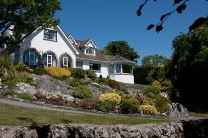 a white house on a hill with flowers in front at Rockcrest House in Kenmare