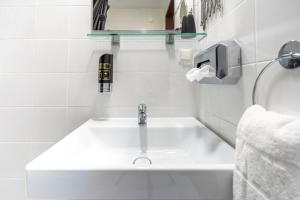 a white bathroom with a sink and a phone at Hotel Enziana Wien in Vienna