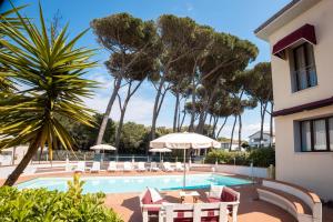 a pool with chairs and umbrellas next to a building at Hotel Kon Tiki in San Vincenzo