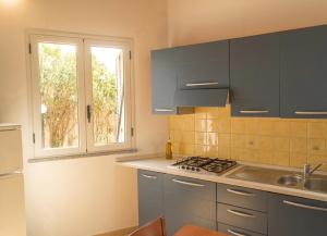 a kitchen with blue cabinets and a sink and a window at House Betania in San Ferdinando