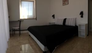 a bedroom with a black bed and a desk at Domestival in Vila Verde dos Francos