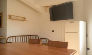 a dining room with a table and a television on the wall at House Betania in San Ferdinando