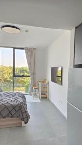 a white bedroom with a bed and a window at Kuro Homes in Sharjah