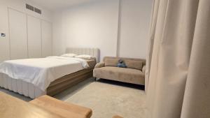 a bedroom with a bed and a chair at Kuro Homes in Sharjah