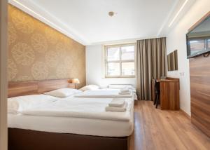 a hotel room with two beds and a desk at Hotel Enziana Wien in Vienna