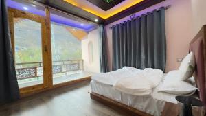 a bedroom with a bed and a balcony with windows at Pahadon Ka Ghar in Sonāmarg