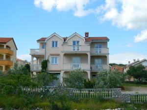 a large white building with a fence in front of it at Apartments Skender in Čižići +21 photos