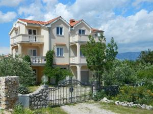 a large house with a fence in front of it at Apartments Skender in Čižići