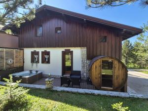 a large wooden house with a deck and a tub at Blidinje Klara in Blidinje