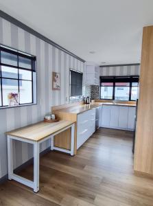 a kitchen with white cabinets and a wooden table at Miro St Guest House in Mount Maunganui