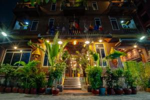 a building with plants in front of it at night at Okay Palace Hotel in Phnom Penh