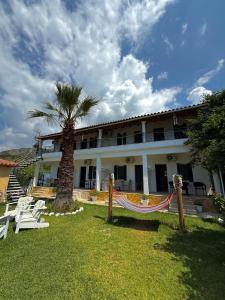 a building with a palm tree and a hammock in front of it at Green House in Himare