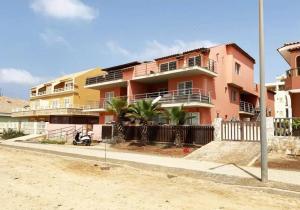 a pink building with palm trees in front of it at Bayview Bliss Appartement just 50 steps from the beach in Santa Maria