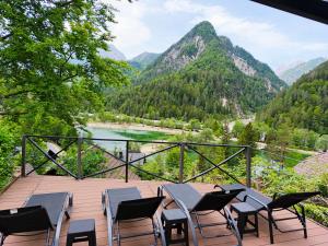 a deck with chairs and tables overlooking a river and mountains at Apartments Smolej Kranjska Gora in Kranjska Gora