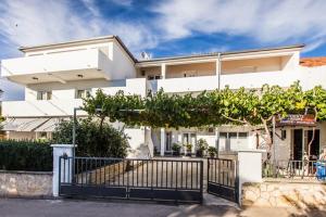 a white building with a gate in front of it at Guesthouse Tuta in Pakoštane
