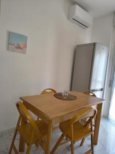 a wooden table and chairs in a kitchen with a refrigerator at Il sorriso romagnolo in Misano Adriatico