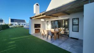 a patio with a table and chairs on a lawn at Apollo on Sea in Velddrif