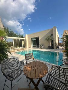 a patio with a table and chairs next to a swimming pool at Villa RRE Green Coast in Palasë