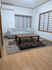 a living room with a couch and a coffee table at はなおか in Takayama