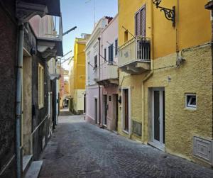 an empty alley way in a city with buildings at Casetta Ismeralda in Carloforte