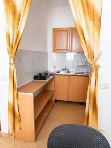 a small kitchen with wooden cabinets and a curtain at Prime rooms in Durrës +25 photos