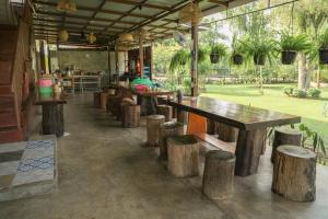 a row of wooden tables and stools in a restaurant at Hindad Nature Resort in Ban Kui Mang