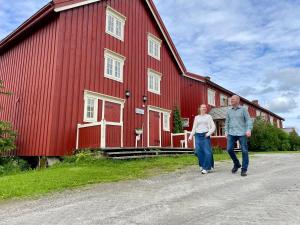 a man and woman walking in front of a red barn at Kulturgården Bjerkem in Steinkjer