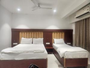 a bedroom with two beds with white sheets at Hotel Metro Palace L&B in Panvel