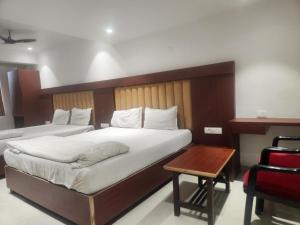 a bedroom with two beds and a table and a chair at Hotel Metro Palace L&B in Panvel