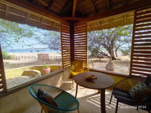 a room with a table and chairs and a view of the beach at Les Collines De Niassam in Palmarin
