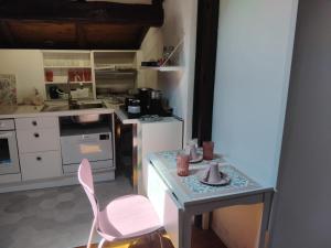 a small kitchen with a table and a pink chair at Sogni in soffitta in Casalecchio di Reno
