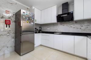 a kitchen with white cabinets and a stainless steel refrigerator at Castelo Sereno in Quinta do Conde