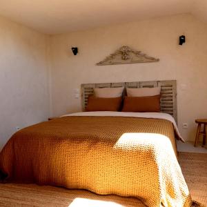 a bedroom with a large bed with an orange comforter at Au Canari gîte de charme in Saint-Sauveur-en-Puisaye